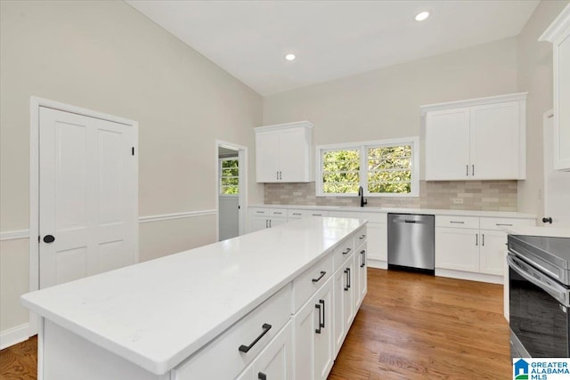 kitchen featuring appliances with stainless steel finishes, wood-type flooring, a center island, and white cabinets