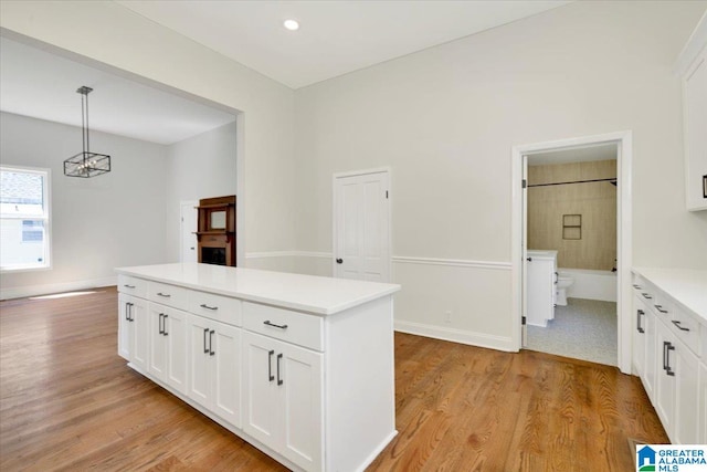 kitchen featuring pendant lighting, white cabinets, light hardwood / wood-style floors, and a notable chandelier