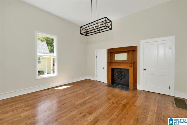 unfurnished living room with a notable chandelier and hardwood / wood-style floors