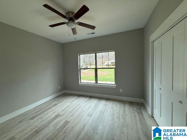 unfurnished bedroom with visible vents, a ceiling fan, baseboards, light wood-type flooring, and a closet