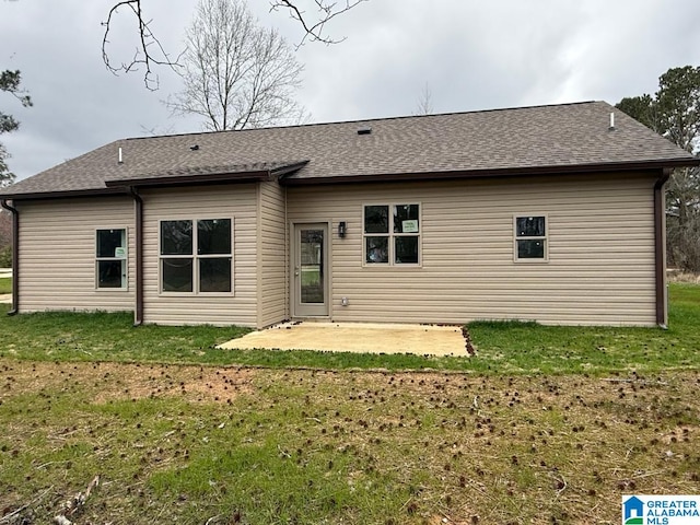 rear view of property featuring a shingled roof, a yard, and a patio