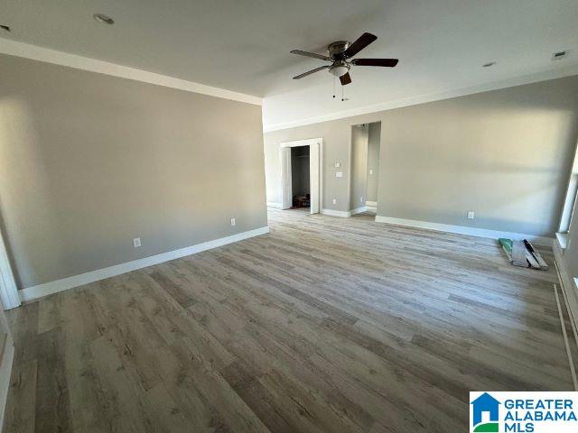 spare room with baseboards, ornamental molding, and wood finished floors