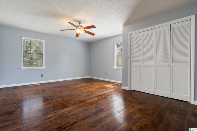 unfurnished bedroom with ceiling fan, a textured ceiling, and dark wood-type flooring