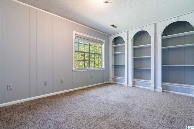 carpeted empty room featuring a textured ceiling and wood walls