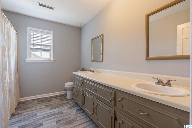 bathroom featuring a textured ceiling, hardwood / wood-style floors, vanity, and toilet