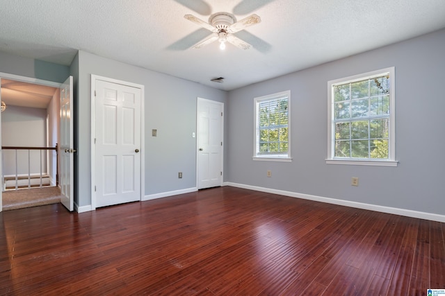 unfurnished bedroom with a textured ceiling, dark hardwood / wood-style floors, and ceiling fan