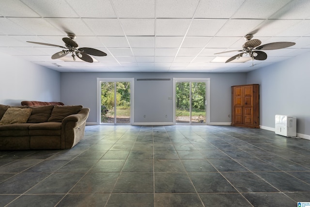 unfurnished living room with a drop ceiling, ceiling fan, and plenty of natural light