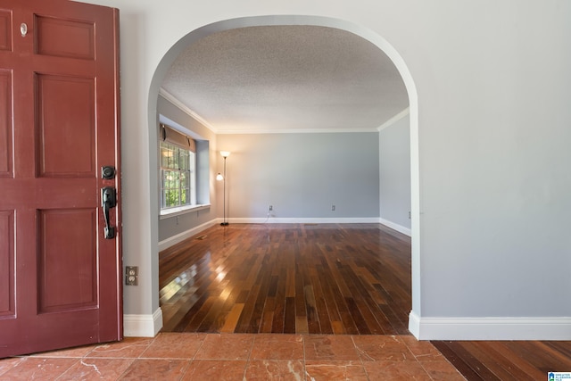 foyer entrance with a textured ceiling, wood-type flooring, and ornamental molding