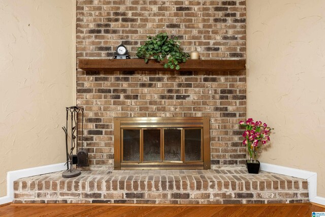 details featuring a brick fireplace and wood finished floors