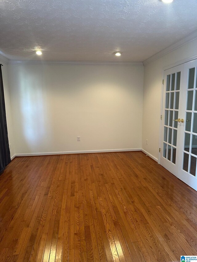 unfurnished room with ornamental molding, baseboards, hardwood / wood-style floors, and a textured ceiling