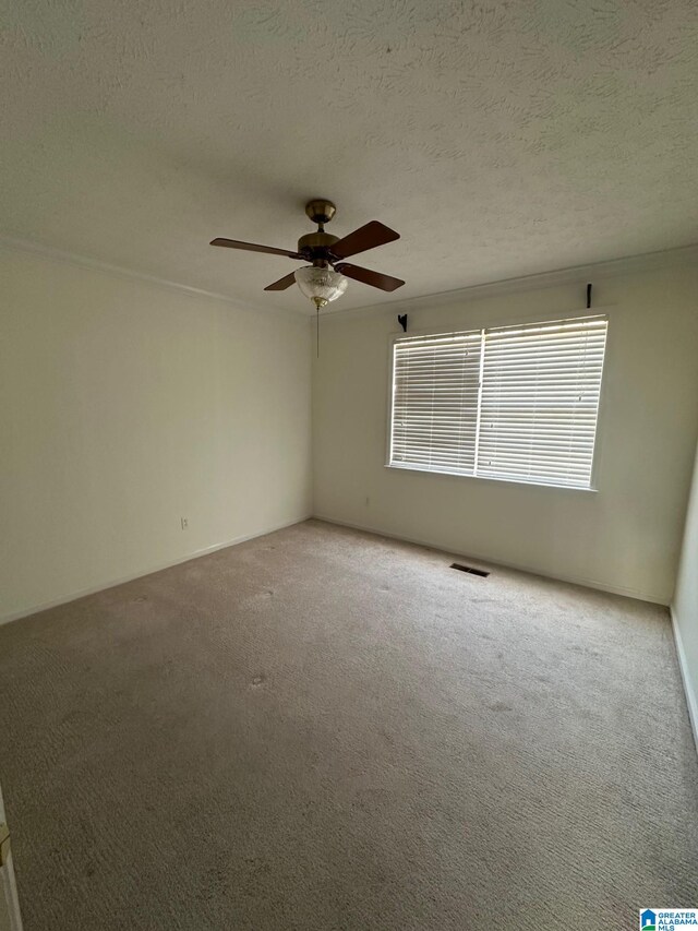 carpeted spare room with visible vents, a textured ceiling, and a ceiling fan