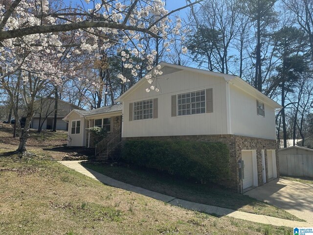 tri-level home featuring a front yard, brick siding, driveway, and an attached garage