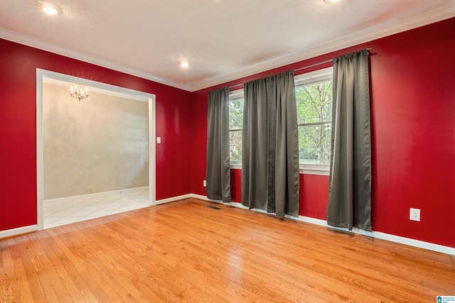 unfurnished room with crown molding, hardwood / wood-style floors, a textured ceiling, and a notable chandelier