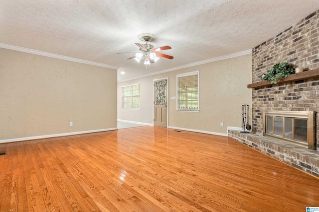 unfurnished living room with a textured ceiling, ornamental molding, light wood-type flooring, and a fireplace