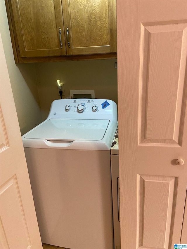 clothes washing area featuring washer and clothes dryer and cabinets