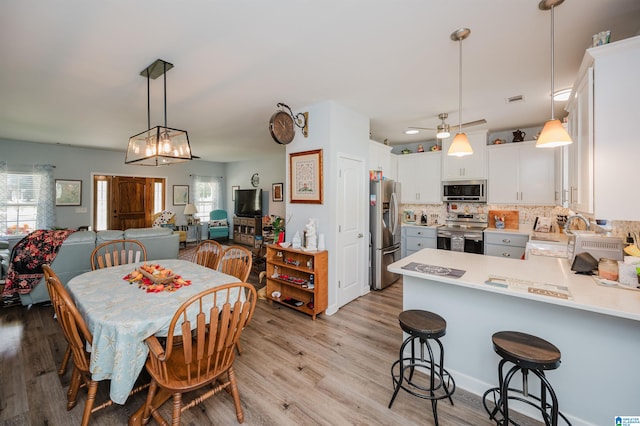 dining room with ceiling fan with notable chandelier, light hardwood / wood-style floors, and sink