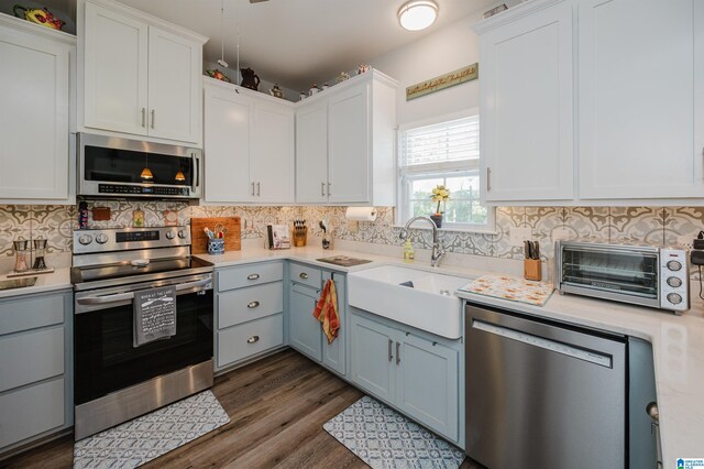 kitchen featuring appliances with stainless steel finishes, dark hardwood / wood-style flooring, and white cabinetry