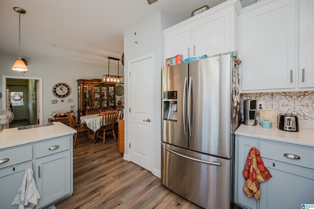 kitchen with hanging light fixtures, backsplash, white cabinetry, stainless steel refrigerator with ice dispenser, and hardwood / wood-style floors