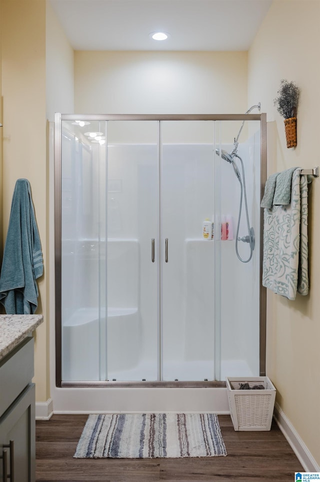 bathroom with hardwood / wood-style flooring, vanity, and an enclosed shower