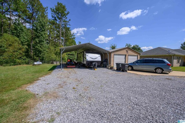 view of front facade with a front yard, a carport, an outbuilding, and a garage