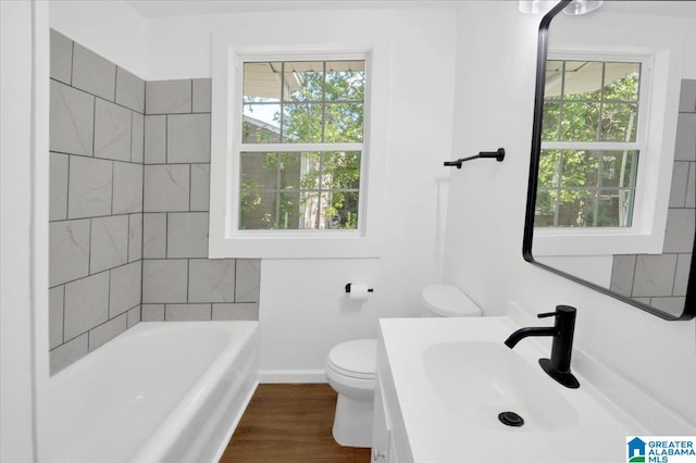 bathroom featuring wood-type flooring, toilet, a healthy amount of sunlight, and a tub