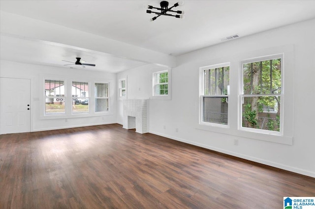 unfurnished living room featuring a brick fireplace, plenty of natural light, and dark wood-type flooring