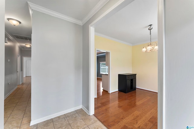 hallway featuring ornamental molding, light wood-type flooring, and an inviting chandelier