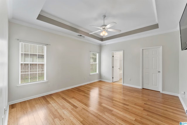 unfurnished bedroom with ceiling fan, light hardwood / wood-style flooring, a raised ceiling, and multiple windows