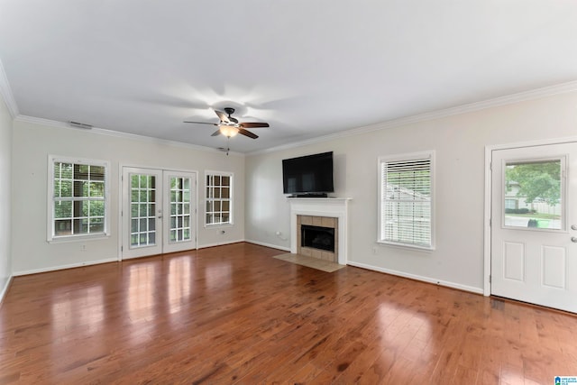 unfurnished living room with a tile fireplace, crown molding, ceiling fan, and hardwood / wood-style flooring