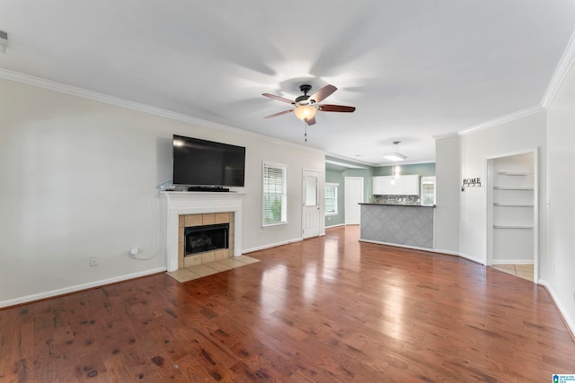 unfurnished living room featuring wood-type flooring, a fireplace, ornamental molding, and ceiling fan