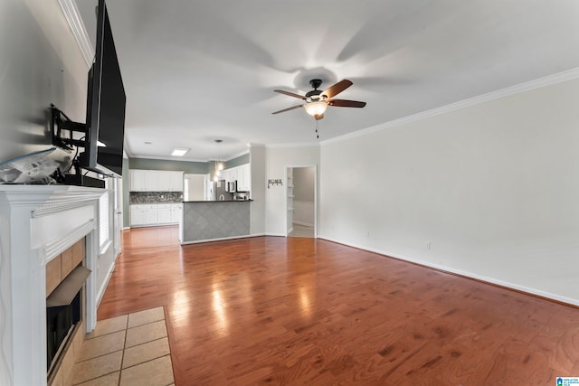 unfurnished living room featuring ceiling fan, crown molding, light hardwood / wood-style floors, and a tile fireplace