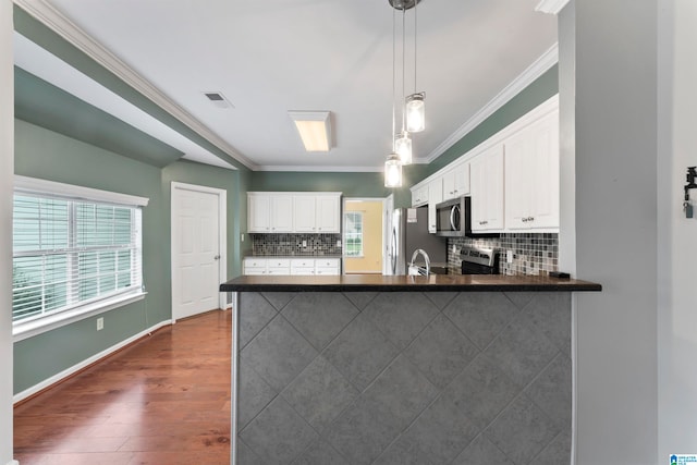 kitchen featuring white cabinets, hanging light fixtures, kitchen peninsula, backsplash, and appliances with stainless steel finishes