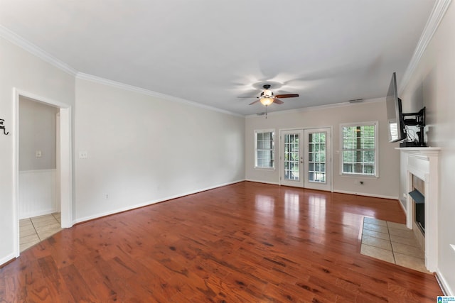 unfurnished living room with ceiling fan, hardwood / wood-style flooring, a tiled fireplace, and crown molding