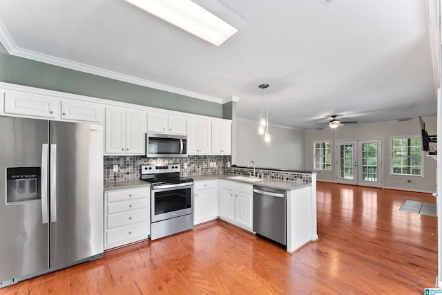 kitchen featuring white cabinetry, kitchen peninsula, light hardwood / wood-style flooring, appliances with stainless steel finishes, and decorative light fixtures