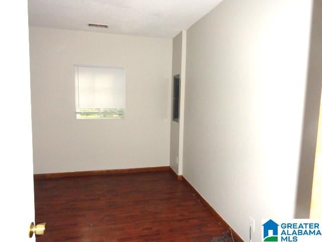 unfurnished room with electric panel and dark wood-type flooring