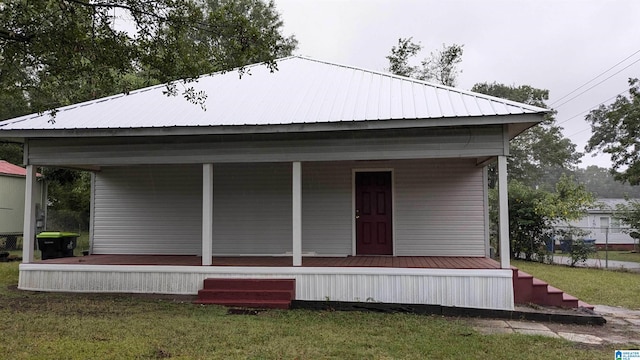 rear view of property featuring covered porch and a yard