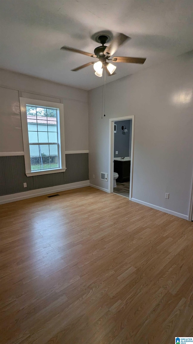 empty room featuring light hardwood / wood-style floors, ceiling fan, and wood walls