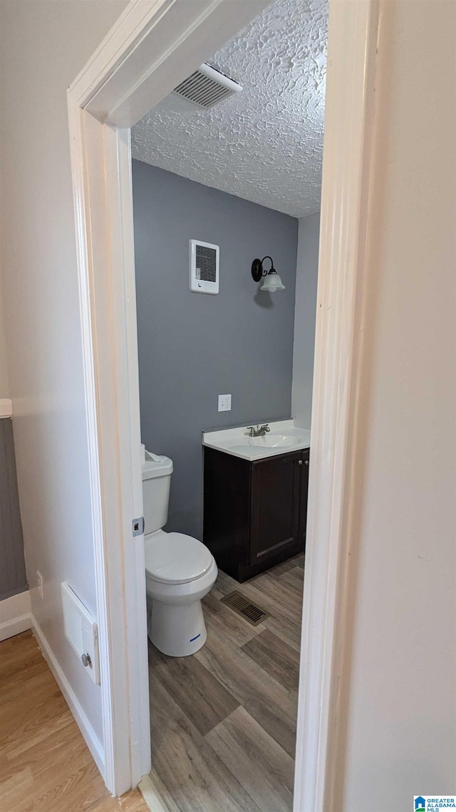 bathroom featuring a textured ceiling, vanity, toilet, and hardwood / wood-style flooring