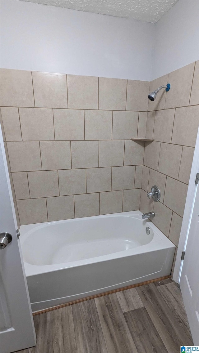 bathroom featuring a textured ceiling, tiled shower / bath combo, and wood-type flooring