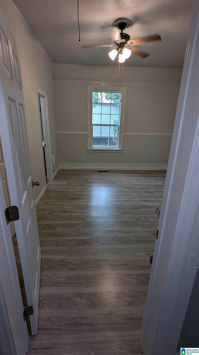 empty room featuring dark wood-type flooring and ceiling fan