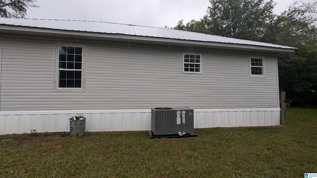 view of side of property with central AC unit and a yard