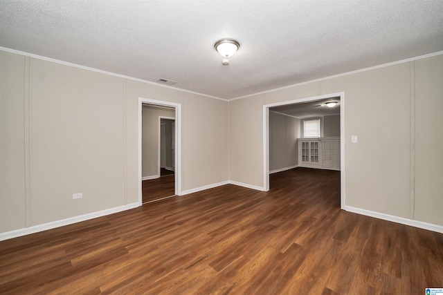 unfurnished room featuring a textured ceiling, ornamental molding, and dark wood-type flooring