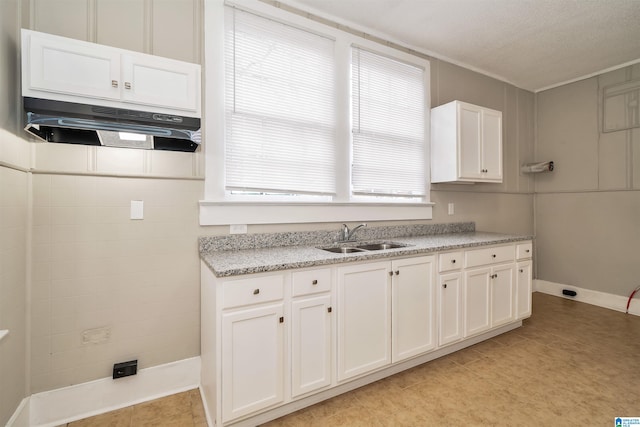 kitchen featuring white cabinets, sink, light stone counters, and plenty of natural light