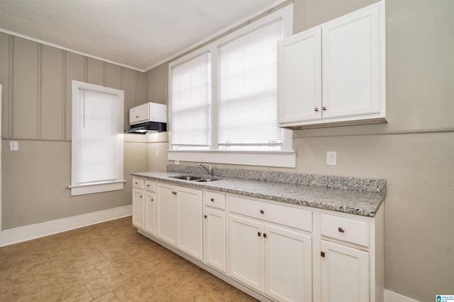 kitchen featuring light stone countertops, plenty of natural light, sink, and white cabinetry