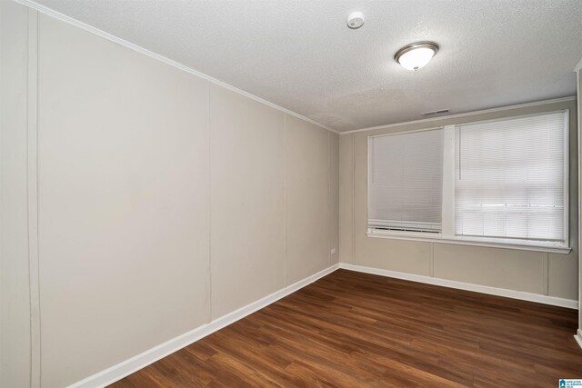 empty room with ornamental molding, a textured ceiling, and dark wood-type flooring