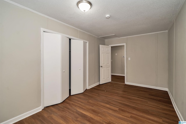 unfurnished bedroom with a textured ceiling, crown molding, dark hardwood / wood-style flooring, and a closet