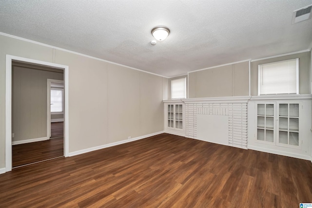 unfurnished living room featuring a wealth of natural light, a textured ceiling, a fireplace, and dark hardwood / wood-style flooring