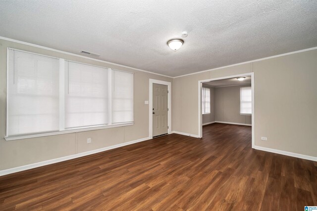 spare room with a textured ceiling, crown molding, and dark hardwood / wood-style flooring