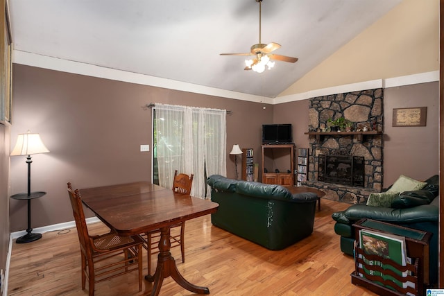 living room featuring high vaulted ceiling, wood-type flooring, ceiling fan, and a stone fireplace