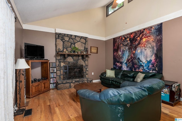 living room with a stone fireplace, light hardwood / wood-style floors, and high vaulted ceiling